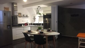 Una cocina moderna con comedor, equipada con electrodomésticos de acero inoxidable, una mesa blanca y sillas negras.