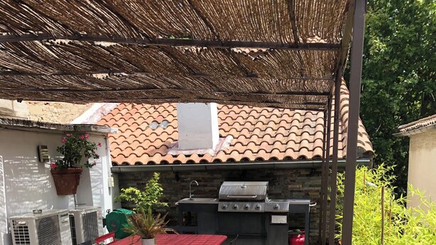 Un patio con una mesa y sillas rojas, una parrilla y una planta en maceta.