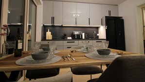 A modern kitchen with grey cabinets, a wooden dining table set with glassware and cutlery, and a wine bottle on the counter. - Mr. Grey by the lake (Zeuthen)