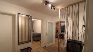 A modern room with a wooden floor, a bed, a desk, and a chair. There is a mirror on the wall and a small stool. - Mr. Grey by the lake (Zeuthen)