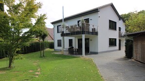 A two-story house with a balcony, a paved driveway, and a well-maintained lawn. - Mr. Grey by the lake (Zeuthen)