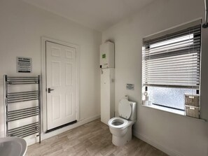 A small, clean bathroom with a toilet, a towel rack, and a window with blinds.
