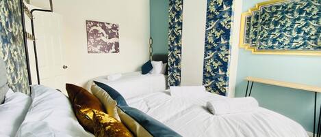 A bedroom with a bed, pillows, a wall-mounted light fixture, a door, and a framed picture.