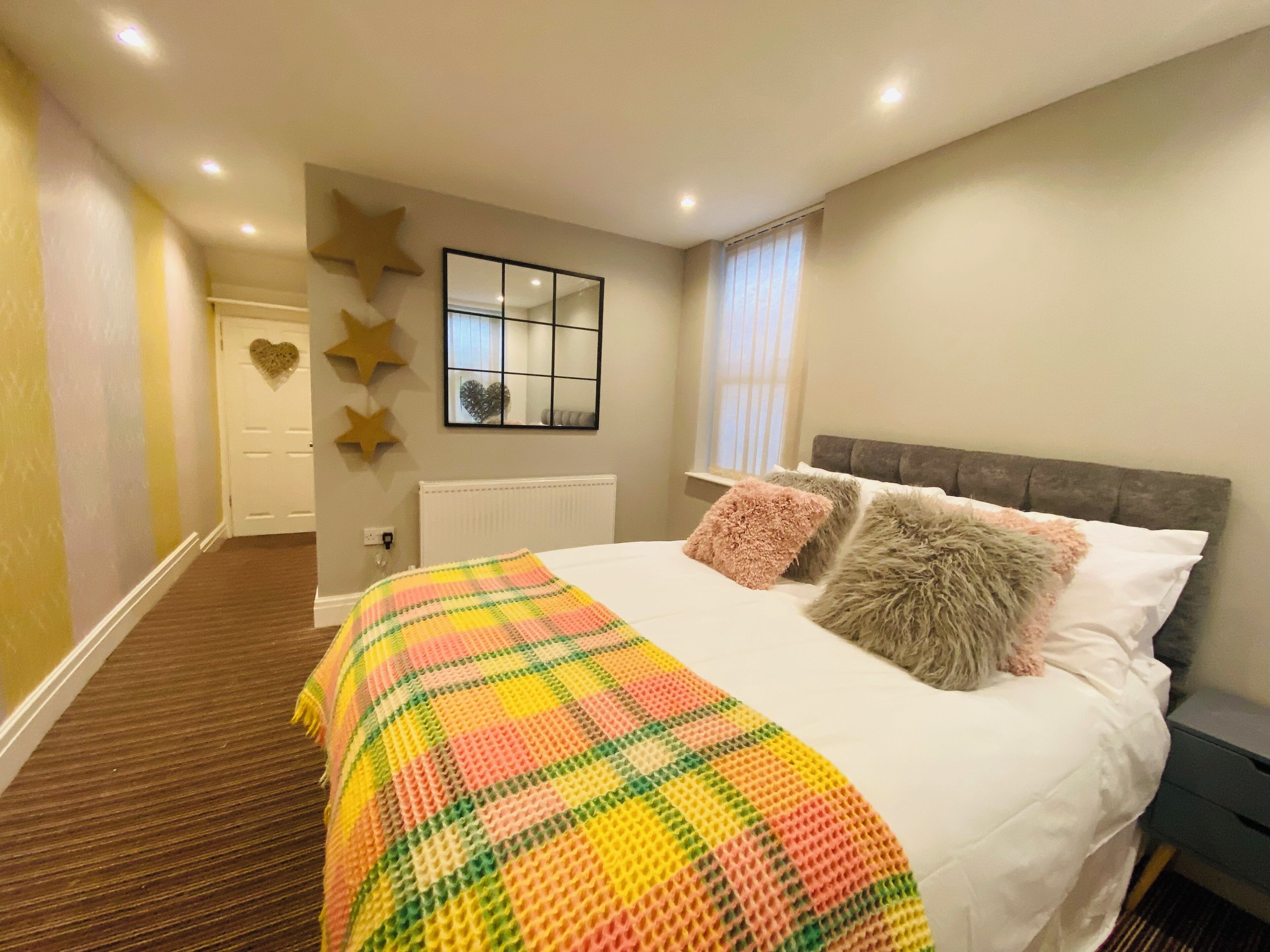 A bedroom with a bed, a window, a mirror, and decorative star-shaped items on the wall.