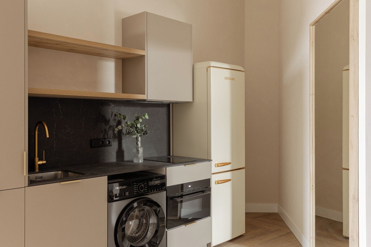 A compact kitchen with a washing machine, oven, and a refrigerator.