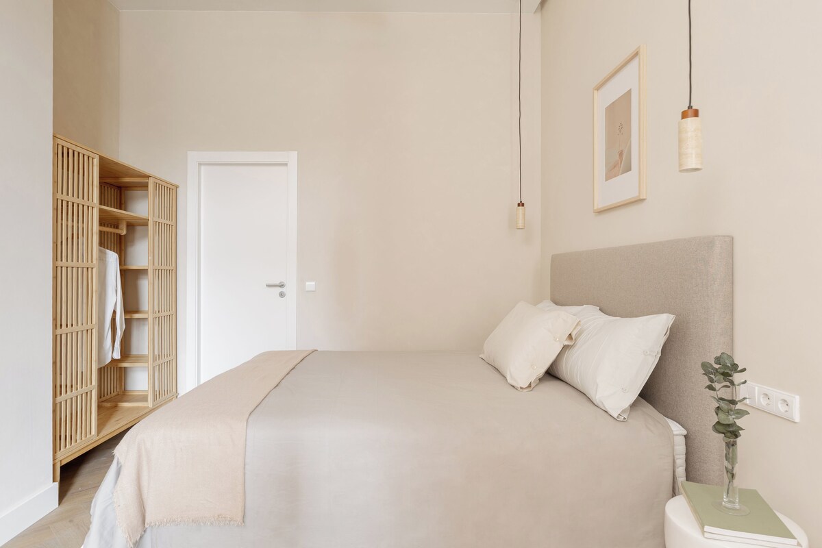 Quarto com cama, mesa de cabeceira e guarda-roupa.