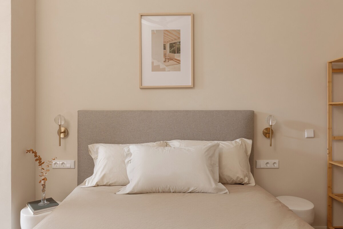 Ein Schlafzimmer mit Bett, Nachttischen, einem gerahmten Bild an der Wand und einer Nachttischlampe.