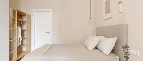 A bedroom with a bed, bedside table, and a wardrobe.