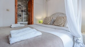 Ein Schlafzimmer mit Bett, weißen Vorhängen, einer Holztür und einer wandmontierten Klimaanlage.