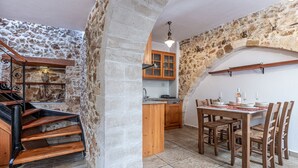 Eine rustikale Küche mit Steinwänden, Holzschränken und einem Essbereich mit Tisch und Stühlen.