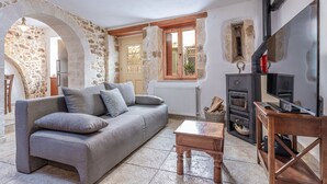 Ein gemütliches Wohnzimmer mit einem Steingewölbe, einer Couch, einem Holztisch, einem Kamin und einem Fernseher.