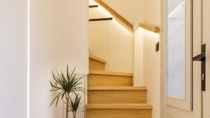 A wooden staircase with a potted plant, leading to a door with a frosted glass panel.