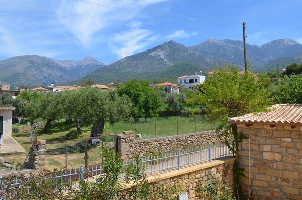 Zona residencial con muros de piedra, un camino empedrado y casas con tejados de tejas rojas.