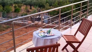 Un balcon avec une table dressée pour deux personnes, offrant une vue sur un paysage côtier.