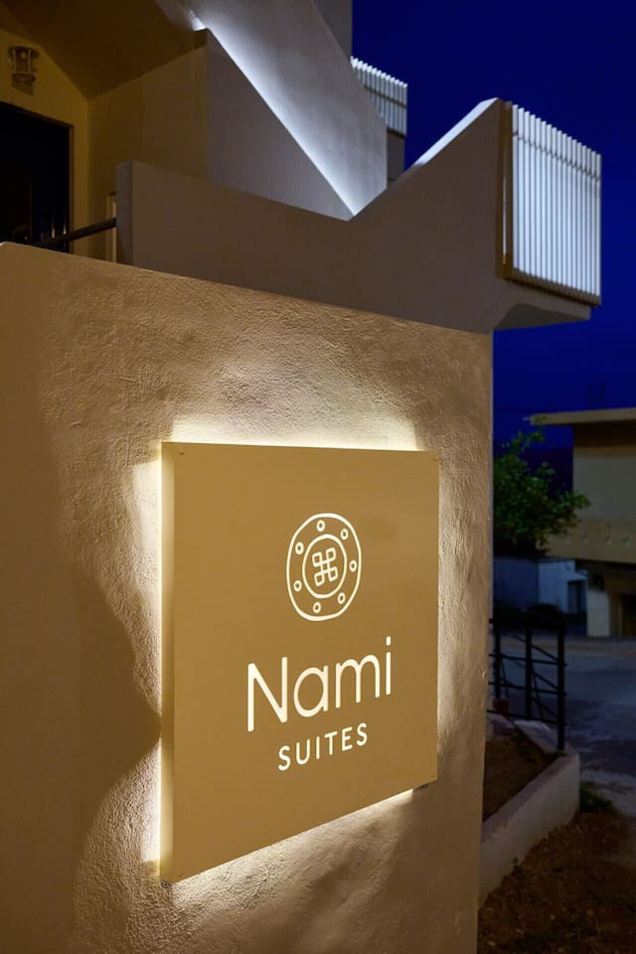 Letrero de 'Nami Suites' con diseño moderno y logotipo iluminado.