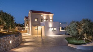 A modern two-story house with a stone wall and a paved driveway. - Casa Galatas | Private pool |The Wisers Living (Chania)