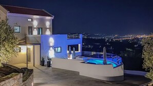A modern outdoor pool area with a view of the city at night. - Casa Galatas | Private pool |The Wisers Living (Chania)