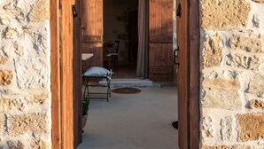 A stone-walled entrance with wooden doors and a bench inside. - Delta-Rho | Kalami | Crete (Kalami)