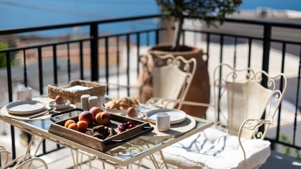 A balcony with a table set for breakfast, including fruits and pastries, overlooking a scenic view. - Delta-Rho | Kalami | Crete (Kalami)