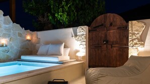 A cozy outdoor seating area with a stone wall, a wooden door, and a pool. - Delta-Rho | Kalami | Crete (Kalami)