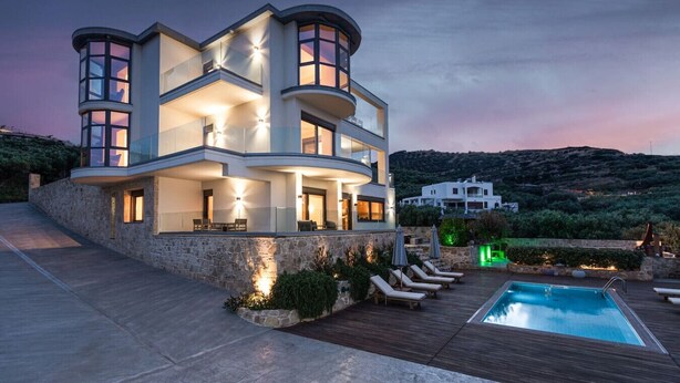 A modern multi-story house with a pool and outdoor seating.