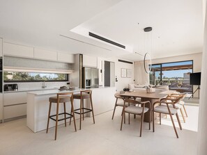 A modern kitchen with a central island, bar stools, and a dining area with a table and chairs.