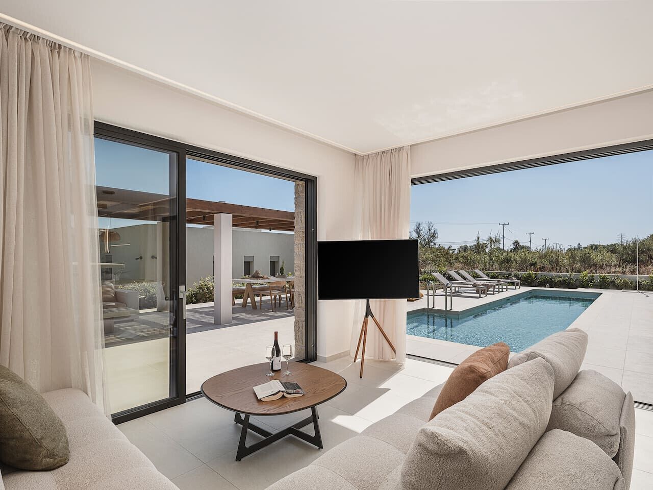 Una sala de estar moderna con televisor grande, piscina y vistas al exterior.