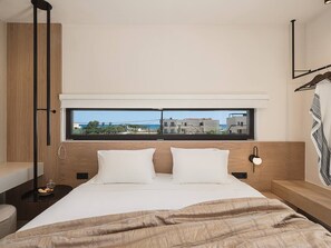 A modern bedroom with a large bed, a bedside table, a floor lamp, and a window with a city view.