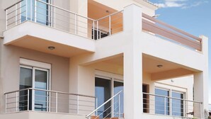 A two-story building with a balcony, a staircase, and a small garden area. - Casa Minervos | Unique Views (Souda)