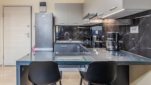 Une cuisine moderne dotée d’un îlot central en verre, de deux chaises noires, d’une machine à café et d’une cuisinière.