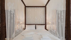 A hotel room with a large bed, white linens, and a decorative headboard. - Villa Geraniotis | Chania (Gerani)