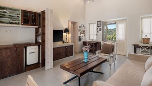 A spacious living area with a wooden dining table, a sofa, and a kitchen area with a fridge and cabinets. - Villa Geraniotis | Chania (Gerani)