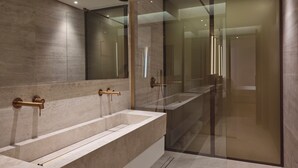 Une salle de bain moderne avec un grand miroir, deux lavabos et une douche à l’italienne.