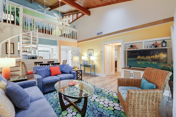 Cozy living area with a high ceiling, sofa, armchair, and dining table.