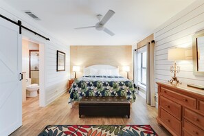 Relax in this serene bedroom with a large bed, bedside tables, and a ceiling fan.