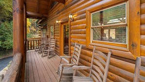 A log cabin with a wooden deck and rocking chairs. - Smoky Mountain Cinema: Showtime in the Smokies (Sevierville)