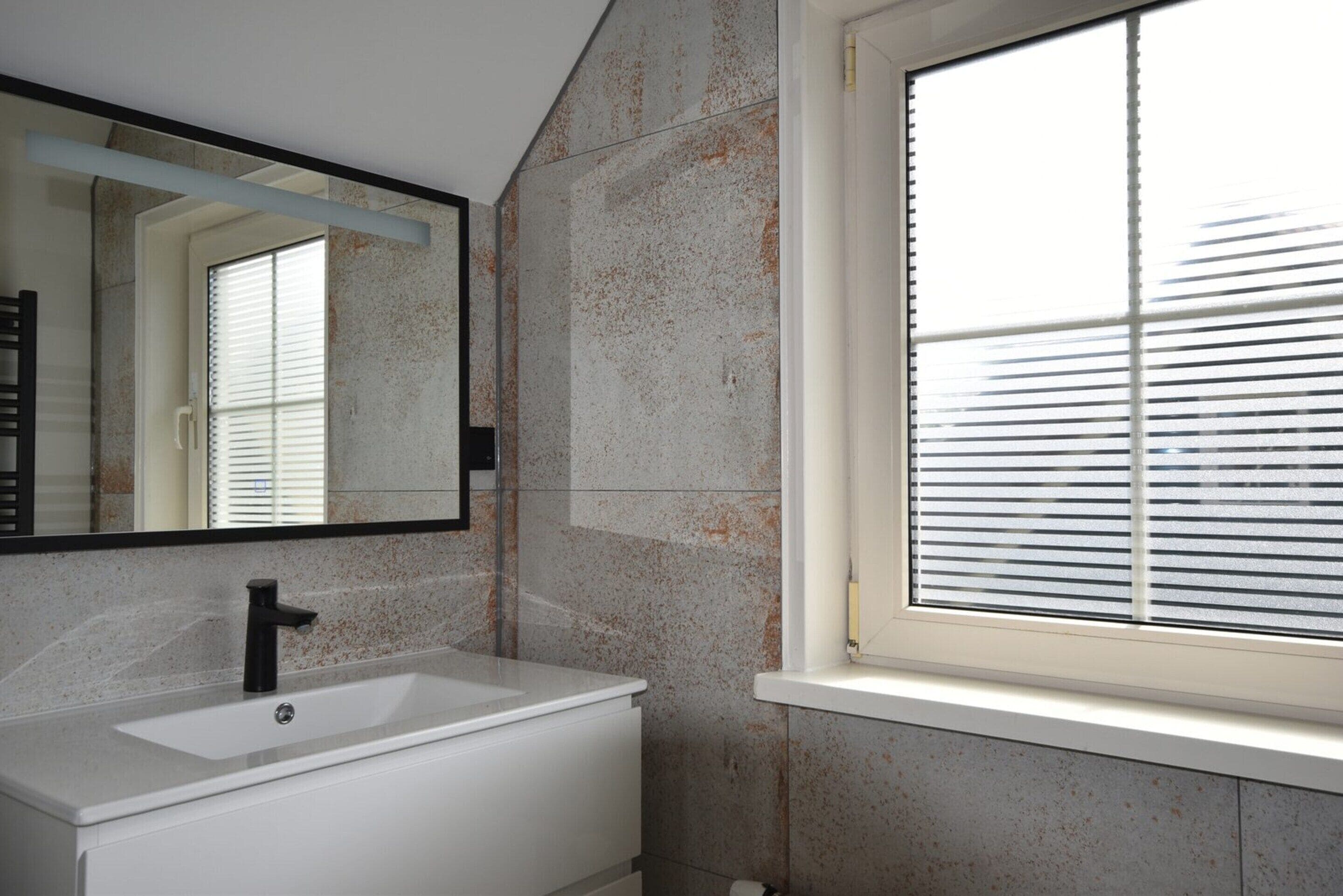 A bathroom with a white sink, black faucet, and a mirror above it.
