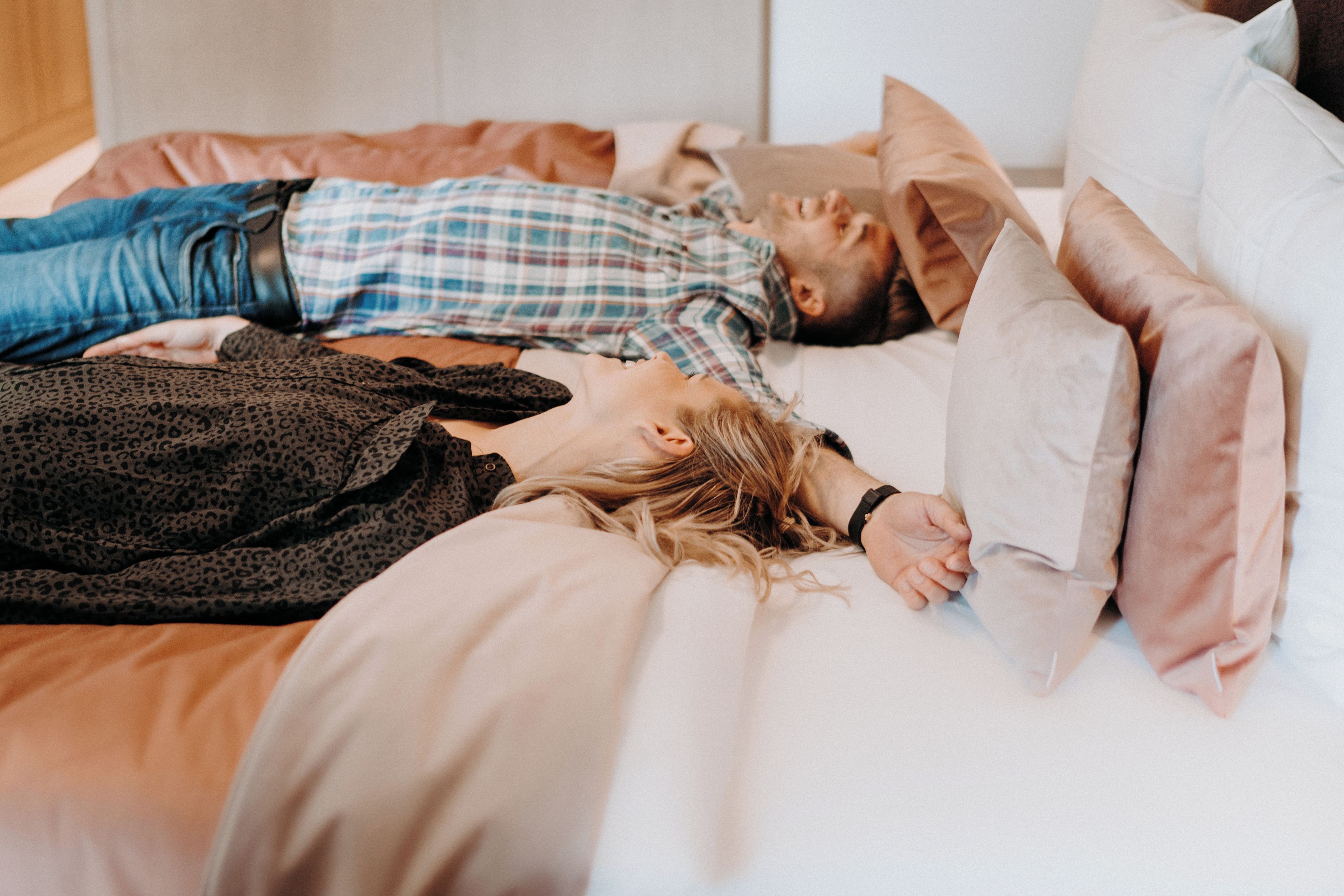 A bed with a person lying on it, covered with a blanket.