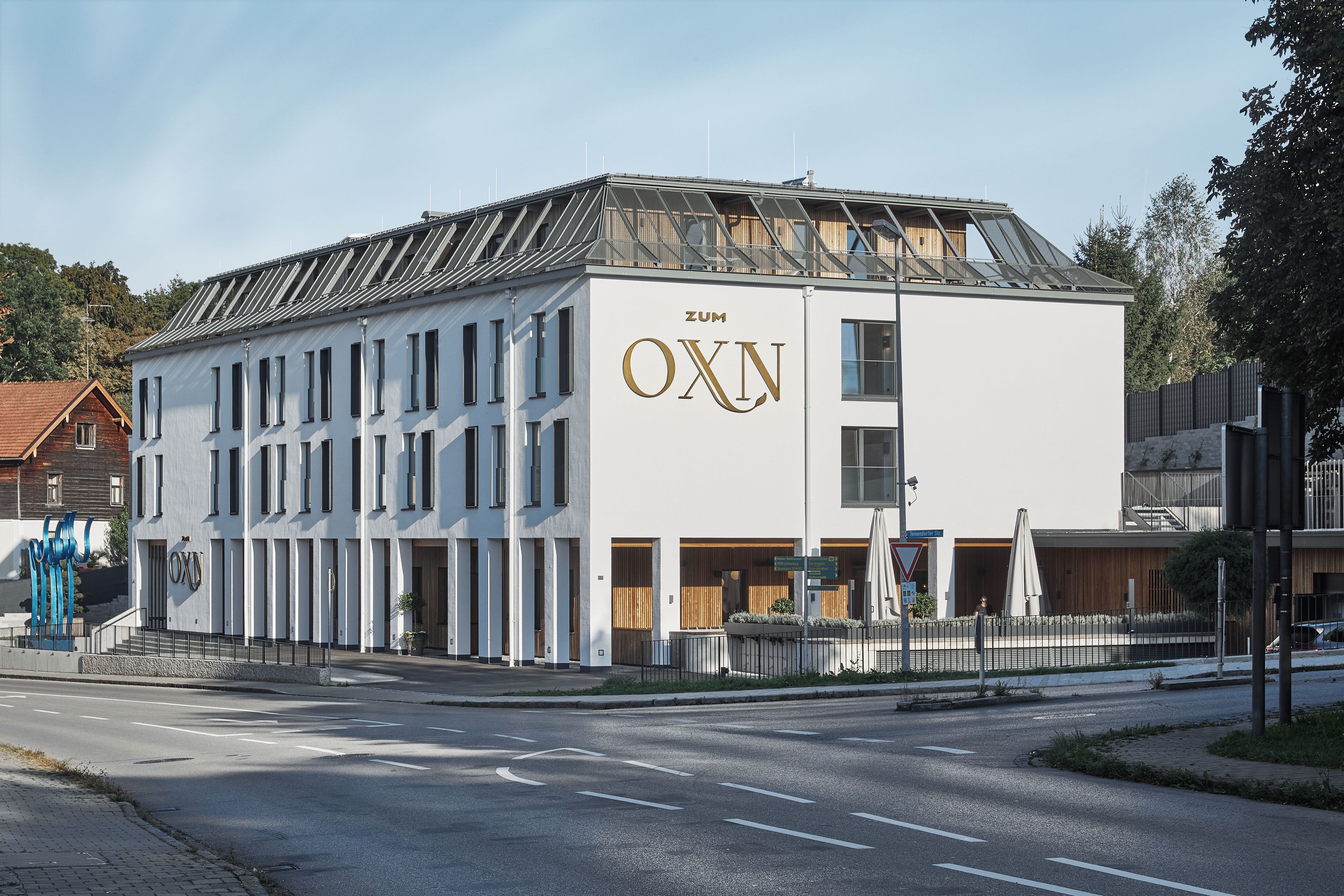 A modern building with a prominent 'OXN' sign on the facade, featuring a symmetrical window arrangement and a flat roof.
