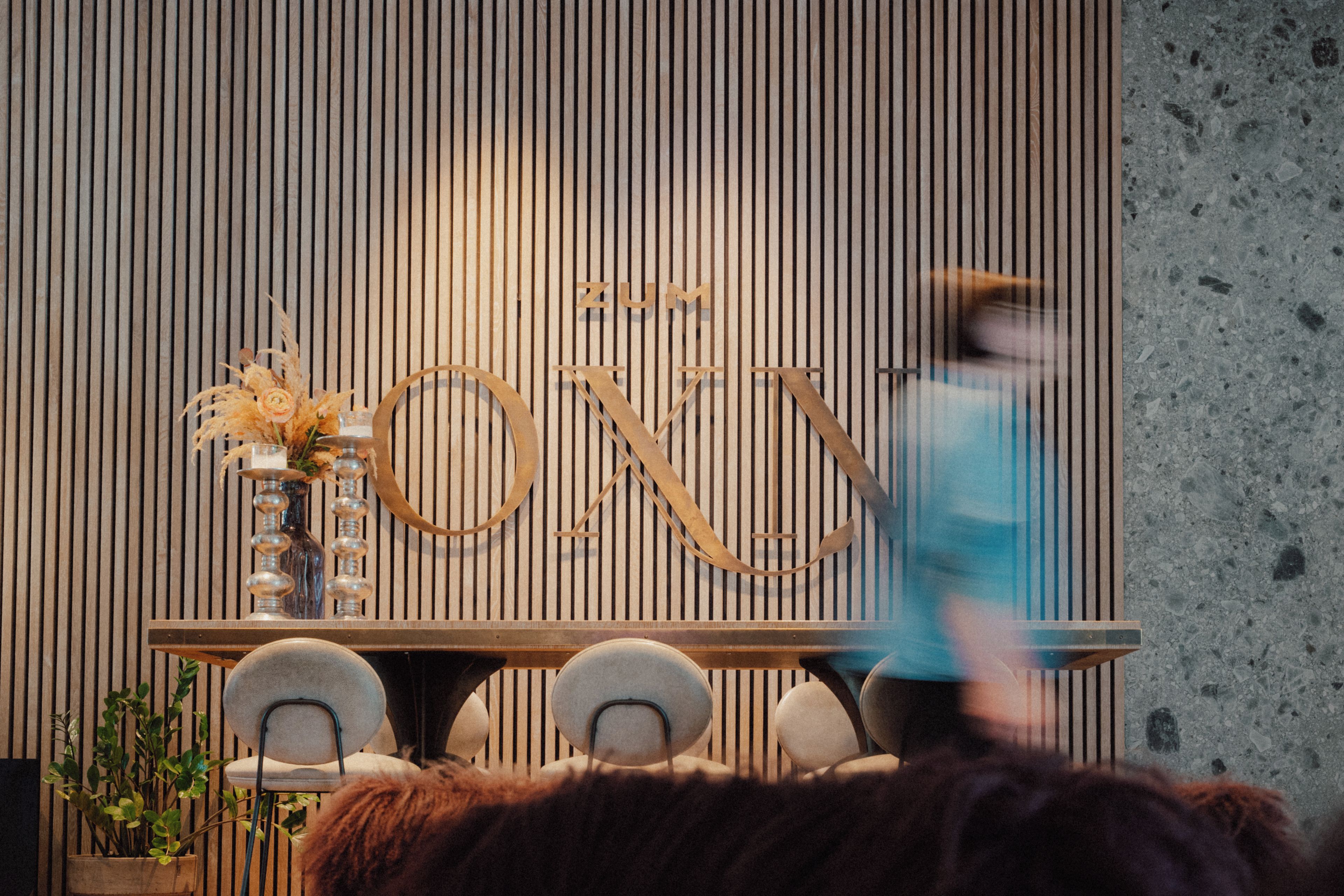 A room with a wooden slatted wall, a table with chairs, and a decorative sign with letters.