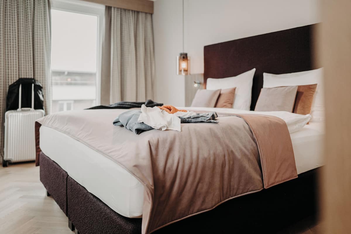 Una habitación de hotel con una cama grande, una maleta y un radiador.