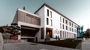 A modern building with a large entrance, a sign reading "OXN," and a staircase leading to the entrance.