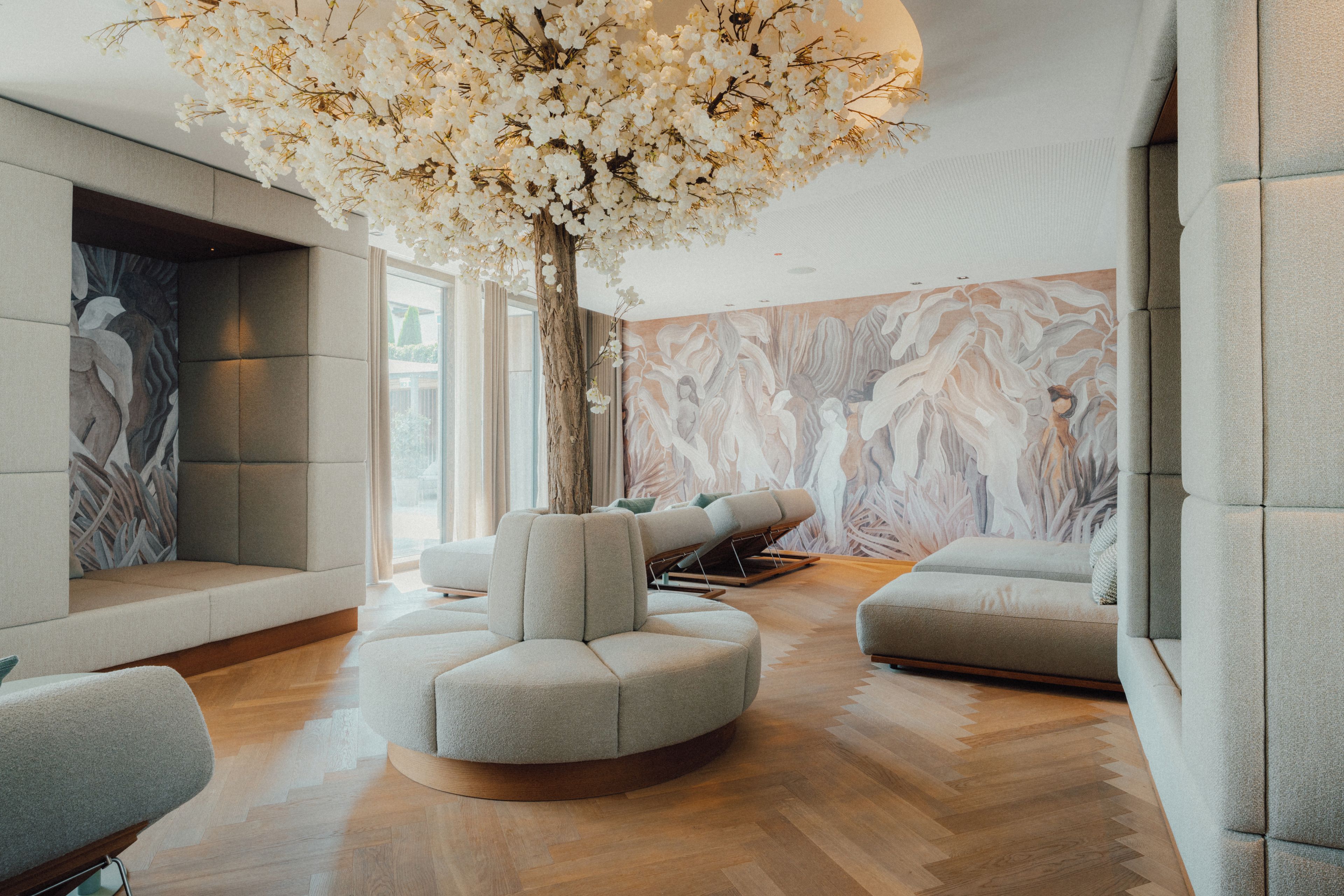 Een modern interieur met een centraal, boomachtige element, zachte zitplaatsen en een wand met een marmerpatroon.