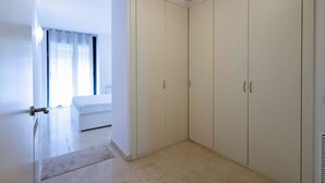 A bedroom with a bed, a walk-in closet, and a window with curtains. - Apartamento para 6 amplio y luminoso en Bonanova (Barcelona)
