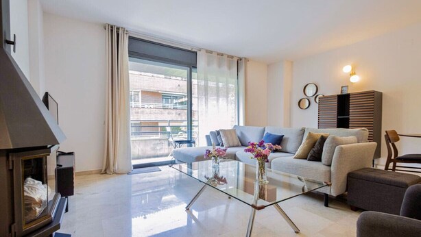 A modern living room with a glass coffee table, a sofa, and a fireplace. - Apartamento para 6 amplio y luminoso en Bonanova (Barcelona)