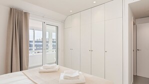 A hotel room with a large bed, a sliding door closet, and a view of the city through the window.