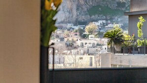 Vista desde una ventana que da a un paisaje urbano con un acantilado destacado y un edificio de columnas.