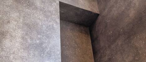 Un área de ducha moderna con cabezal de ducha de mano y llave de pared.