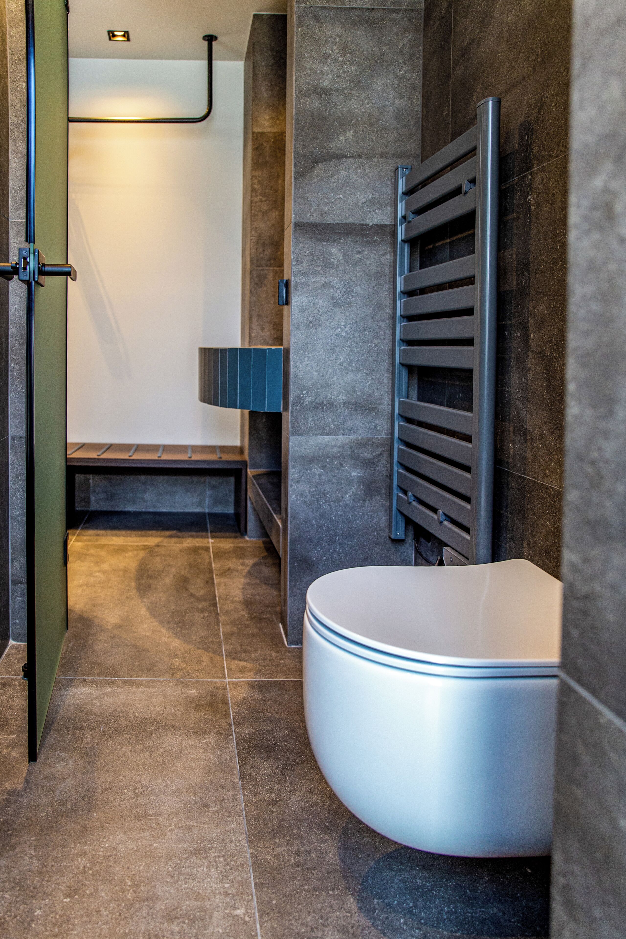 A modern bathroom with a curved bathtub, a towel rack, and a bench.