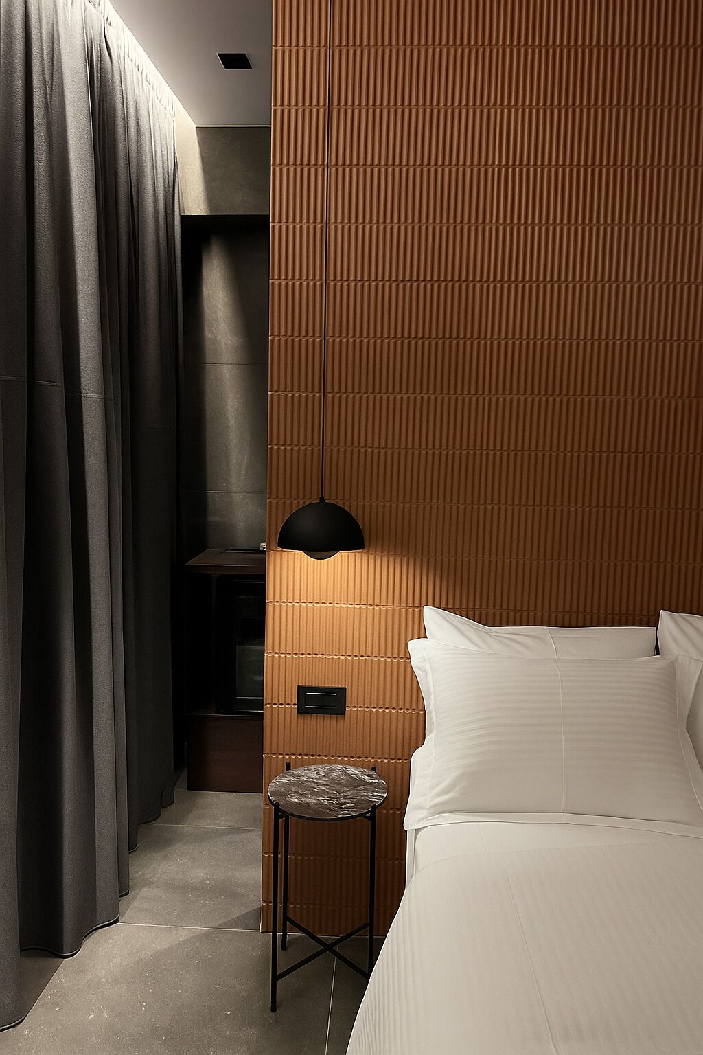 A hotel room with a bed, a small table, a lamp, and a curtain.